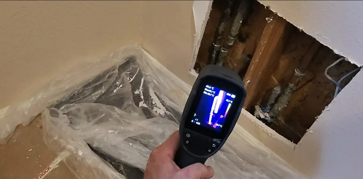 Technician using leak detection equipment around hidden plumbing during leak detection in surprise, az