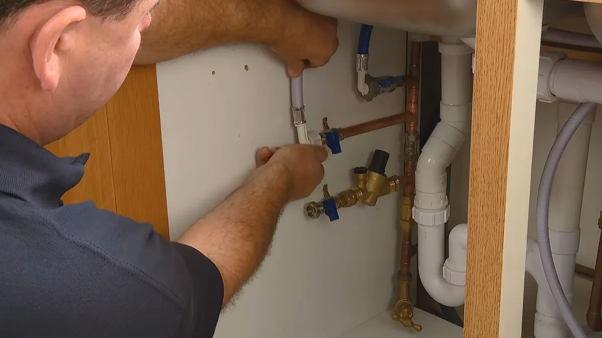 Sink faucet and drain connection being adjusted by hand tools illustrating plumbing defects in new surprise az construction homes