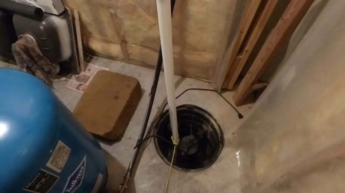 Sump pump basin and pump components being fitted near a foundation during plumbing service in Wittmann, with focus on thumbnail sump pump basin components